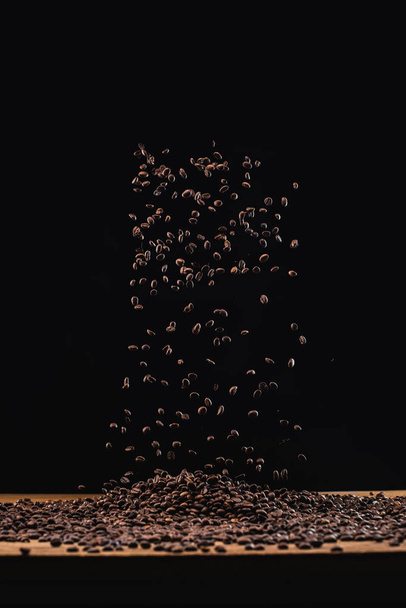 смажені кавові зерна в купі і в повітрі ізольовані на чорному
 - Фото, зображення