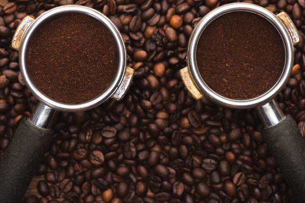 Blick von oben auf frisch geröstete Kaffeebohnen und gemahlenen Kaffee in Filterhalter auf Holztisch - Foto, Bild