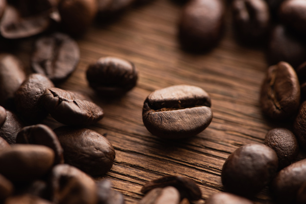 крупним планом вид свіжих обсмажених кавових зерен, розкиданих на дерев'яному столі
 - Фото, зображення