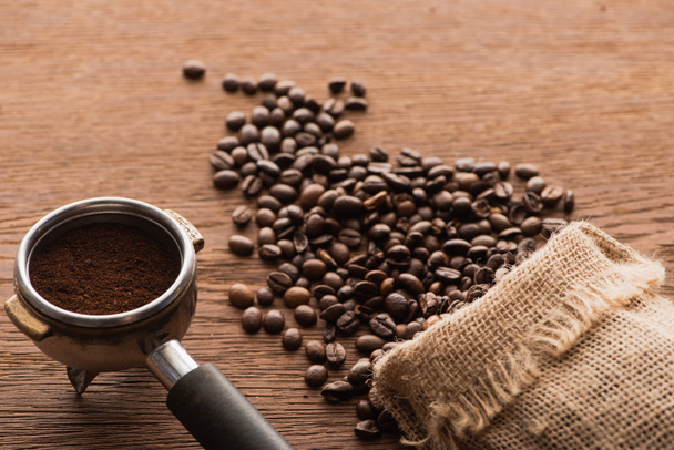 свежий жареный кофе в зернах и молотый кофе в держатель фильтра на деревянный стол
 - Фото, изображение