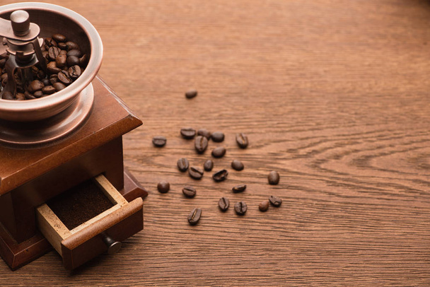frisch geröstete Kaffeebohnen neben Kaffeemühle auf Holztisch - Foto, Bild