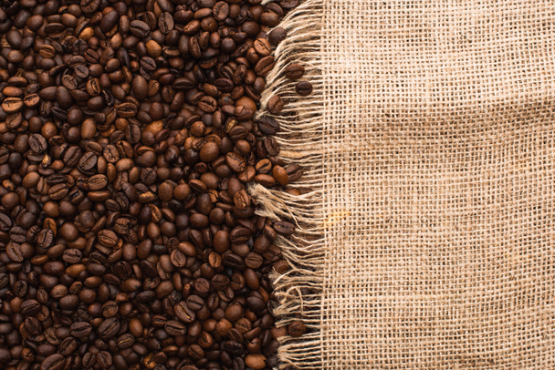 top view of fresh roasted coffee beans and sackcloth - Fotó, kép