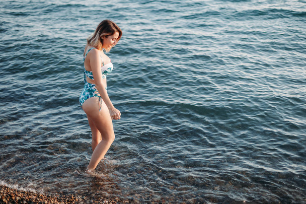 Beautiful young woman goes to the beach in bikini with beautiful - Foto, imagen