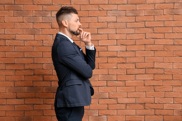 Thoughtful businessman on brick background. Concept of choice - Foto, Imagen