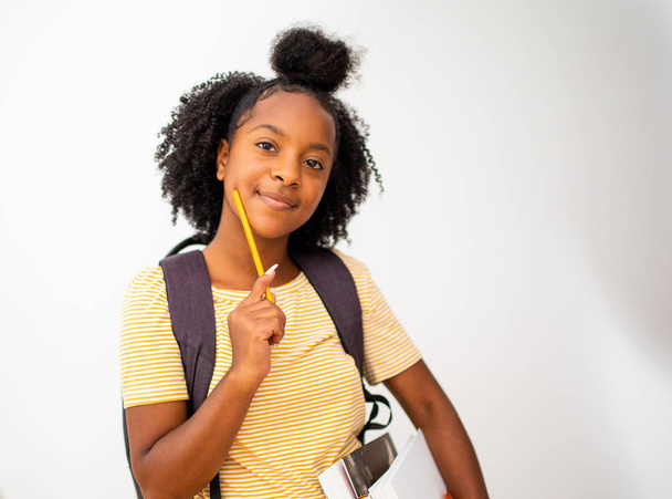 Πορτρέτο της Αφροαμερικανής φοιτήτριας με τσάντα και βιβλία σκέψης - Φωτογραφία, εικόνα