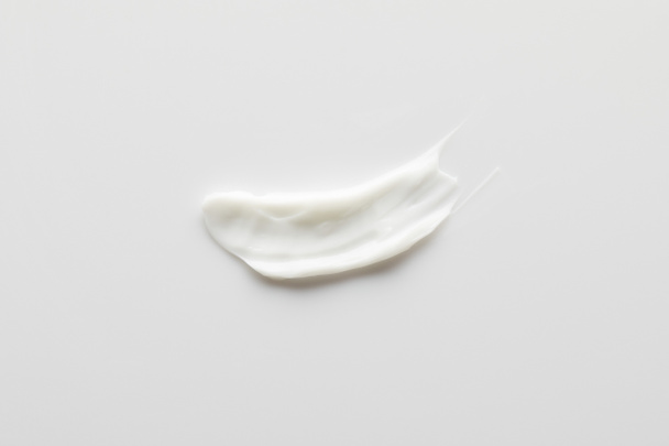 Top view of cosmetic cream brushstroke on grey background - Foto, imagen