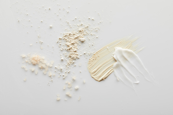 Vue de dessus des coups de pinceau au sel de mer, poudre pour le visage, cosmétique et crème tonique sur fond gris
 - Photo, image