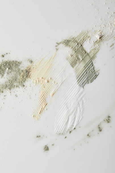 Bovenaanzicht van kleipoeder, cosmetische en tongcrème penseelstreken op grijze achtergrond - Foto, afbeelding