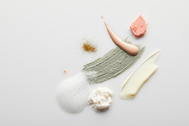 Balçık, kozmetik ve tonik krem fırça darbelerinin üst görüntüsü sabun köpüğü, kızartıcı ve gri arka planda altın parıltılar - Fotoğraf, Görsel