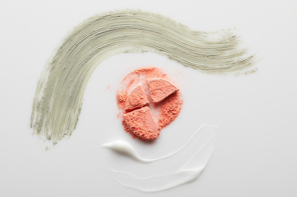 Top view of cosmetic clay and cream brushstrokes with blusher on grey background - Foto, Imagem