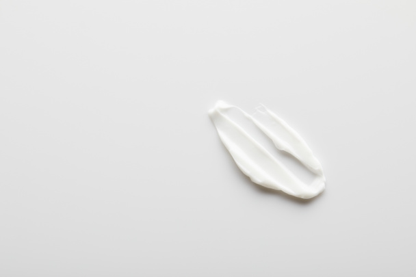 Top view of cosmetic cream brushstroke on grey  - Foto, Imagem