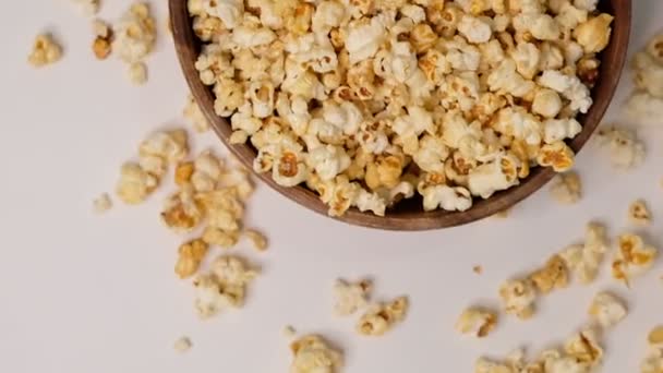 Popcorn in einer hölzernen Schüssel auf weißem Hintergrund. Zeitlupenvideo. Nahaufnahme von oben - Filmmaterial, Video