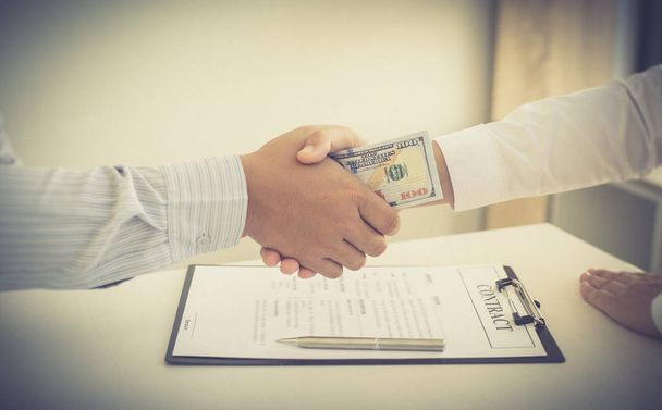  Бизнесмены делают долларовые платежи при подписании инвестиционного соглашения, чтобы быть партнером в незаконной и успешной манере, взяточничество и коррупция концепции
 - Фото, изображение