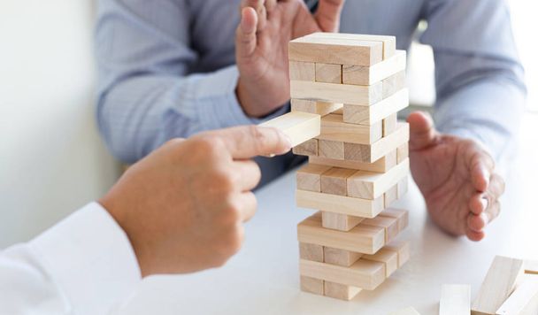 Деловые люди играют в деревянные игры вместе, делят среднюю инвестиционную ценность бизнеса и совместно управляют рисками, альтернативный план риска и стратегию в бизнесе
. - Фото, изображение