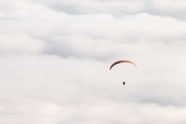 Paraglider flies on the background of clouds on a sunny day. copy space - Fotografie, Obrázek
