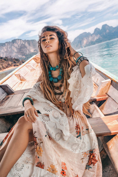 beautiful bohemian woman in dress posing in boat at tropical adventure - Fotó, kép