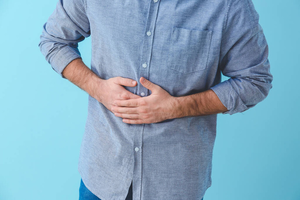 Young man suffering from abdominal pain on color background - Fotoğraf, Görsel