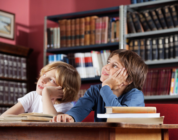 Schoolboys Looking Away While Sitting In Library - Foto, Bild