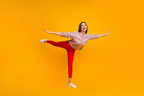 Full size photo of dream dreamy girl enjoy free time holiday hold hand fly like bird do gym exercises wear pullover sneakers isolated over yellow color background - 写真・画像