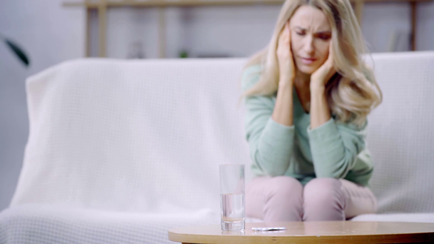 Selektive Fokussierung von Glas Wasser und Frau mit Kopfschmerzen im Hintergrund  - Filmmaterial, Video