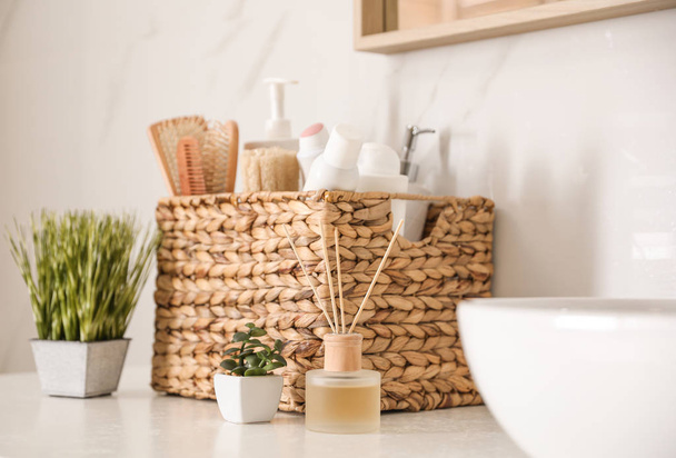 Different toiletries and green plants on countertop in bathroom - Foto, Bild