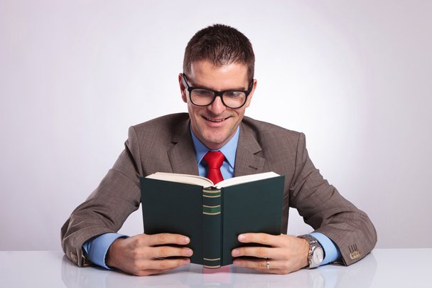 Молодой бизнесмен держит книгу обеими руками
 - Фото, изображение
