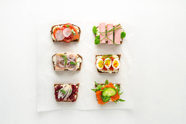 Selección de sándwiches abiertos de smorrebrod danés sobre papel pergamino sobre fondo blanco
 - Foto, imagen