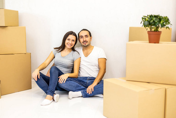 Packed and ready to move in new house. Excited young spouses sitting among carton boxes ready to relocate. - Photo, image