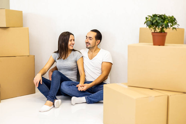 Packed and ready to move in new house. Excited young spouses sitting among carton boxes ready to relocate. - Photo, Image