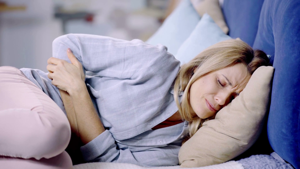kobieta cierpiąca na ból brzucha i leżąca w łóżku  - Materiał filmowy, wideo