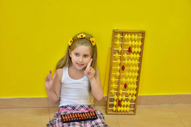 little girl with a wreath on her head and an abacus, - Photo, Image