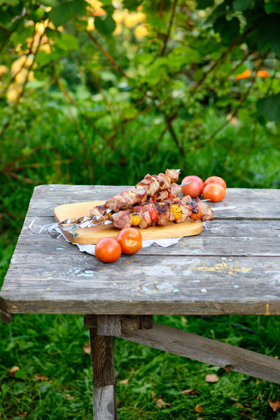 frisch gekochter Grill auf einem Holztisch. Sommer-Mittagessen in der Natur. Leckeres Fleischgericht auf dem Feuer gekocht. - Foto, Bild