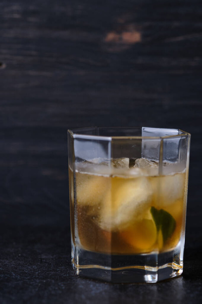 Üveg egy alkoholos koktéllal az asztalon egy bárban. Whiskey citrommal díszített jéggel. - Fotó, kép