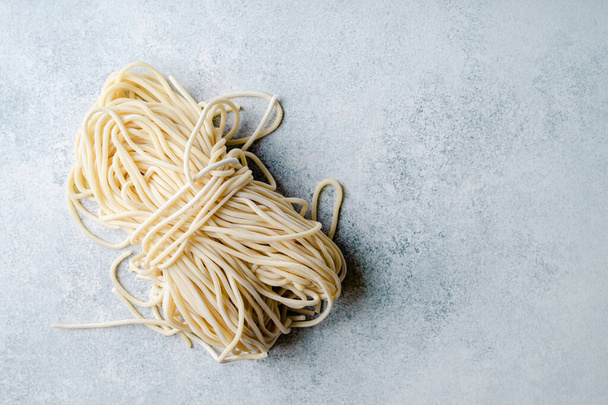 Uncooked fresh pasta on light blue background, closeup view - Foto, afbeelding