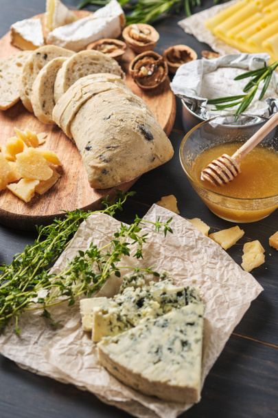 Tasting different types of cheese, honey, nuts and herbs. Several varieties of cheese on a wooden board. Delicatessen for a romantic dinner. - Photo, Image