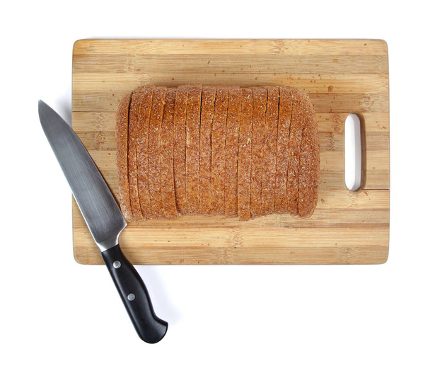 Well sliced loaf of bread on a cutting board with knife. - Fotó, kép