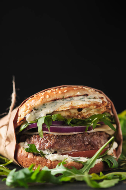 közel a szájvíz burger grillezett marhahússal és friss zöldségekkel. Ízletes amerikai sajtburger fa táblán.  - Fotó, kép