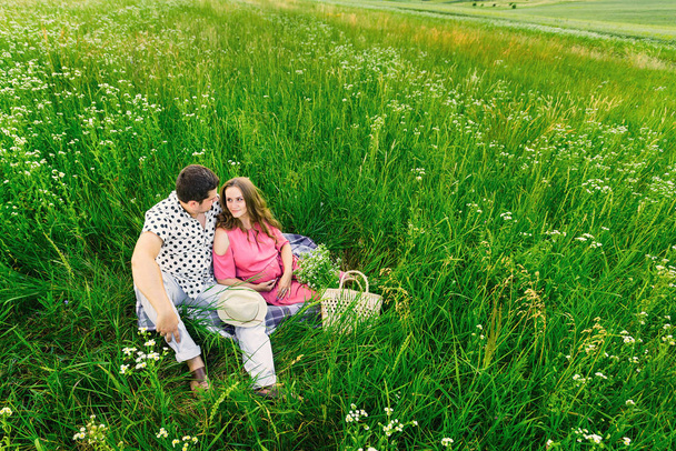 meadow with tall grass and the future parents sit on coverlet. b - Fotoğraf, Görsel