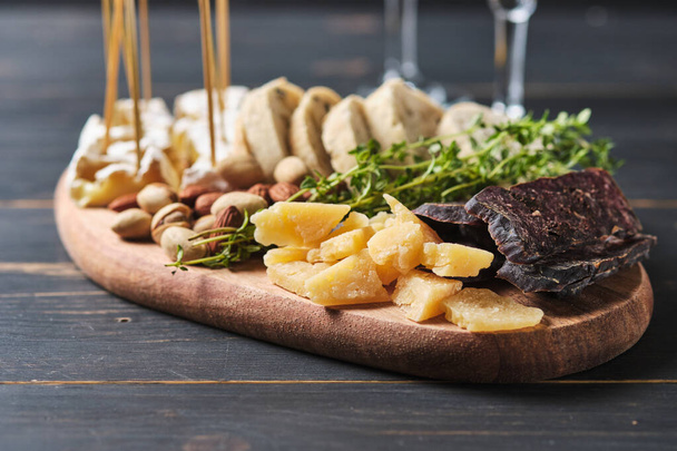 Deliciosos bocadillos. Varias variedades de queso, nueces, ciabatta y salchichas en una antigua mesa de madera. Comida para una cena romántica
. - Foto, Imagen