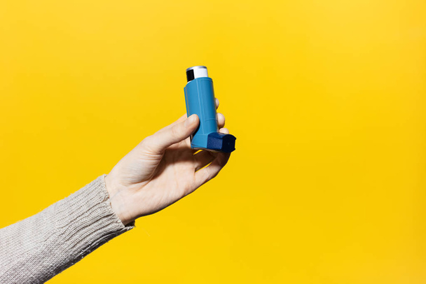 Nahaufnahme der weiblichen Hand mit Asthma-Inhalator auf gelbem Hintergrund. - Foto, Bild