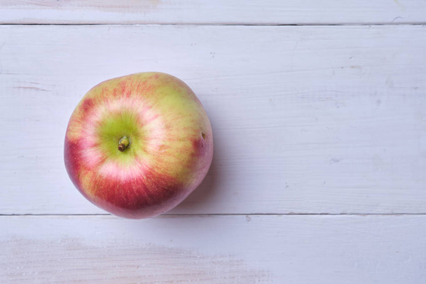Una mela su un tavolo di legno bianco. Posto per testo
. - Foto, immagini