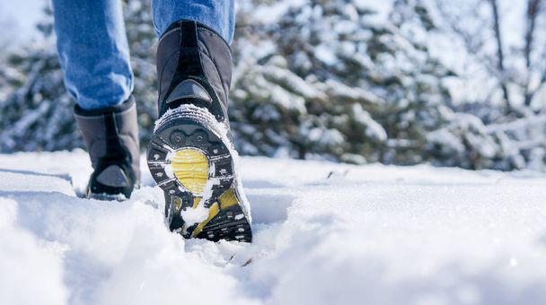 male or female winter boots walking on snowy sleet road - Foto, afbeelding
