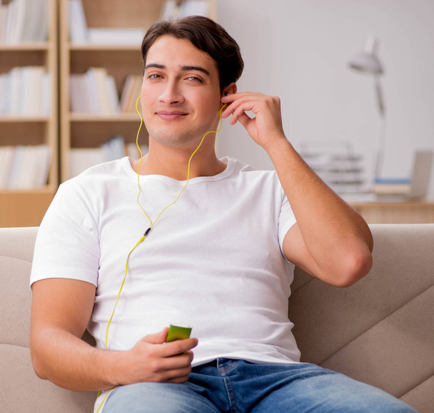Hombre escuchando música sentado en el sofá
 - Foto, imagen