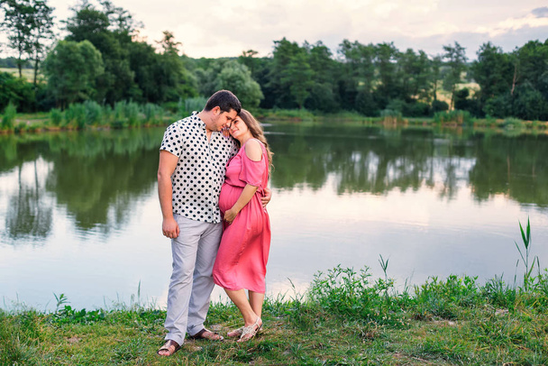 tender hugs of expectant parents on the backdrop of lake and for - Фото, изображение