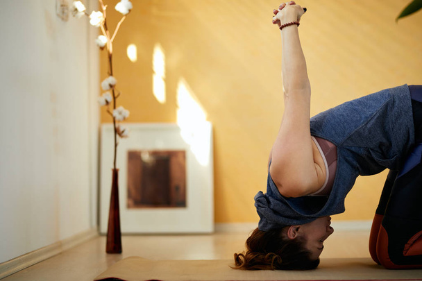 Nahaufnahme einer schlanken, engagierten Yogi-Frau mittleren Alters in Hasen-Yoga-Pose. Morgens, zu Hause. - Foto, Bild