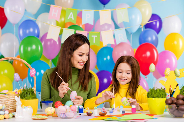 Portrait of nice attractive lovely cheerful cheery girls painting eggs making artwork creating spending time pastime sisters small little offspring - Foto, Imagem