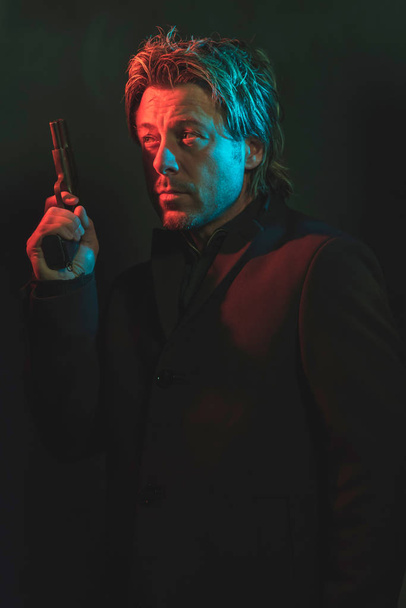 Un homme tenant un pistolet près de sa tête. Illustré par le rouge et le bleu
  - Photo, image