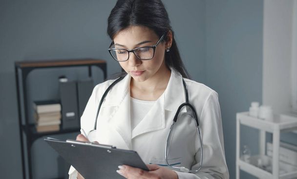 Female doc writing medical chart - Foto, Imagem