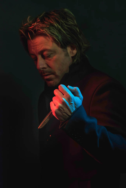 Gruseliger Mann mit Schere in der Hand, beleuchtet von rotem und blauem Licht - Foto, Bild