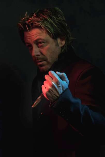 Τρομακτικός άνθρωπος με ψαλίδι στο χέρι φωτίζεται από κόκκινο και μπλε Ligh - Φωτογραφία, εικόνα